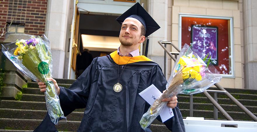 一名学生在SPU毕业典礼上戴上兜帽后走出麦金利大厅